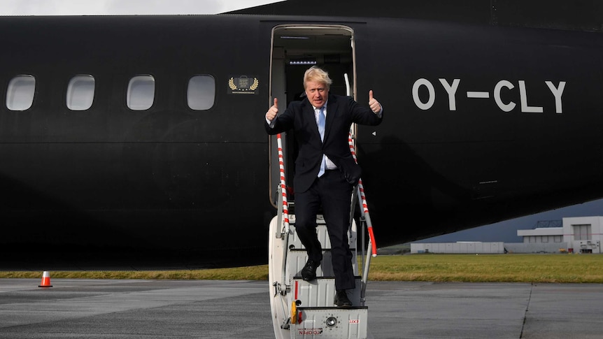 Boris Johnson giving the thumbs up while walking down the steps of a plane