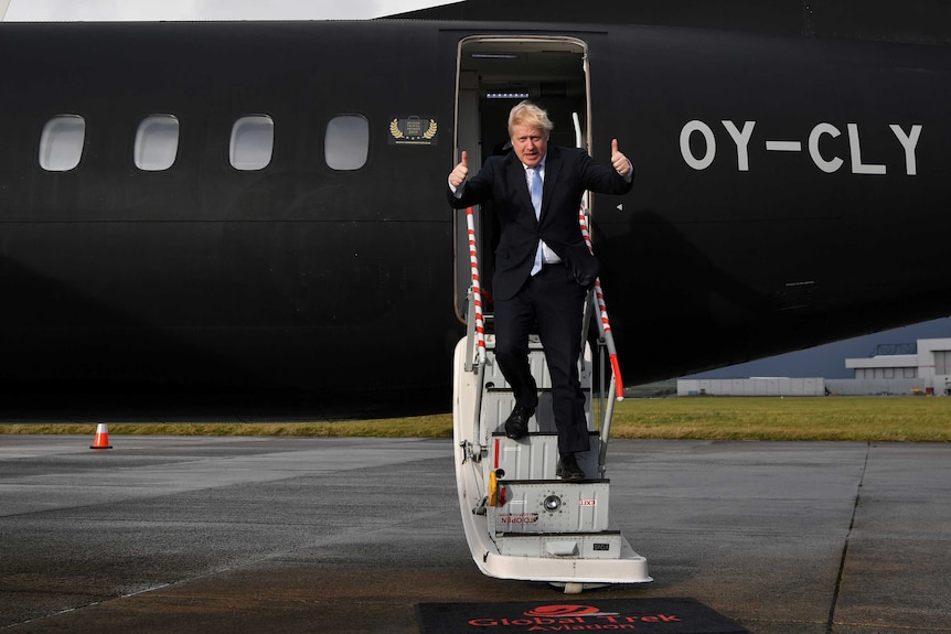 Boris Johnson giving the thumbs up while walking down the steps of a plane