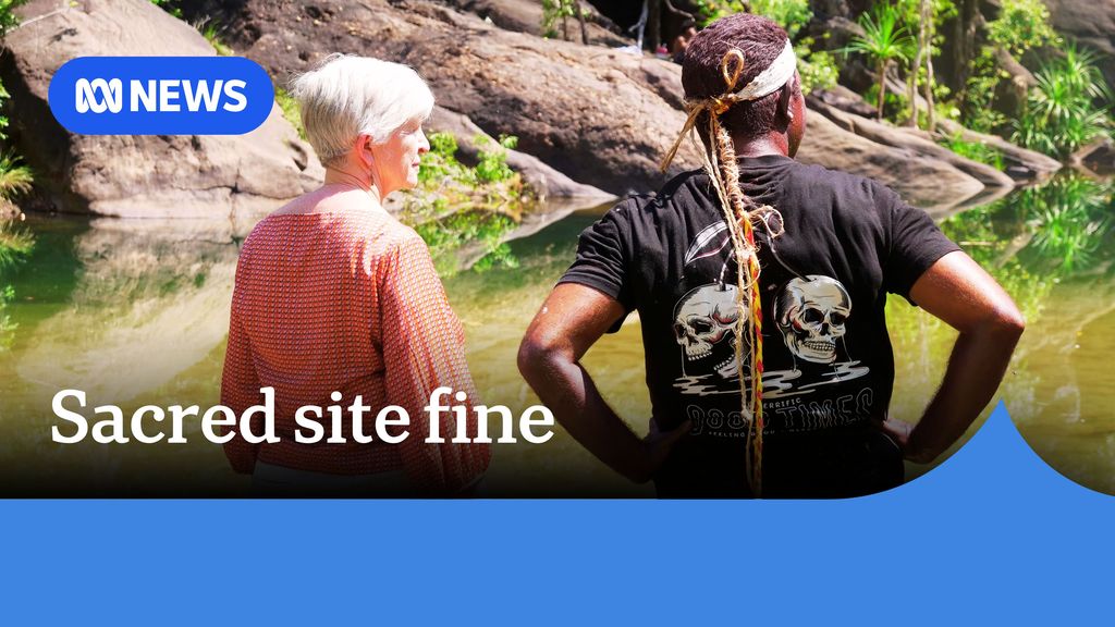 Sacred site fine. Photo of the backs of an older lady and a younger man looking across a body of natural water at Gunlom Falls. 