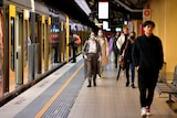 rail commuters walk along a platform
