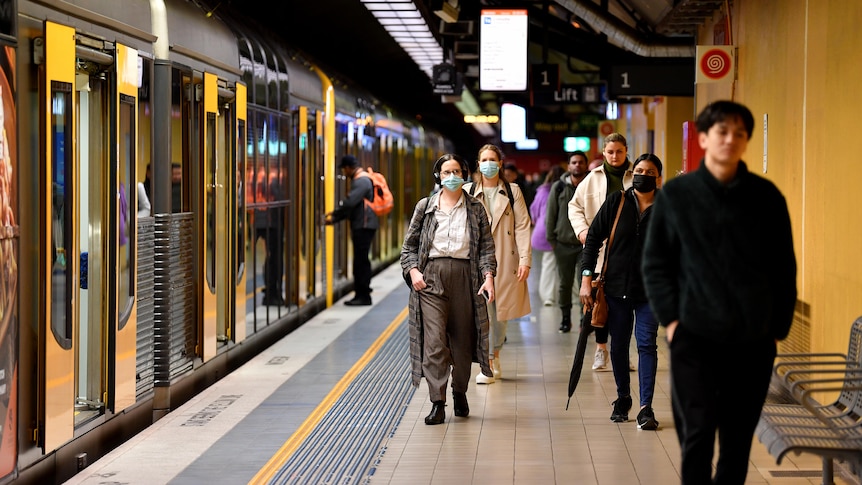 rail commuters walk along a platform