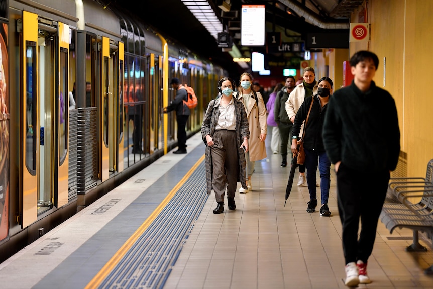 rail commuters walk along a platform