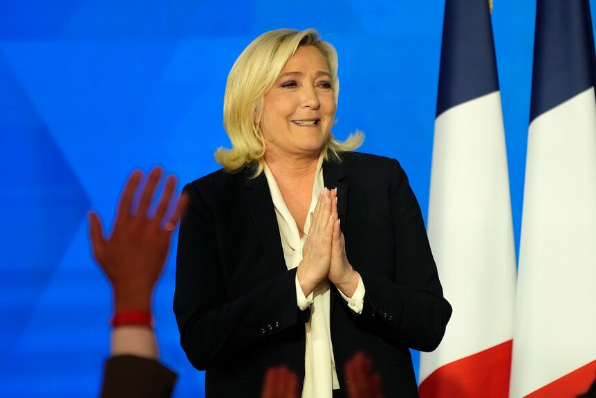 Far-right leader Marine Le Pen speaks next to several French flags