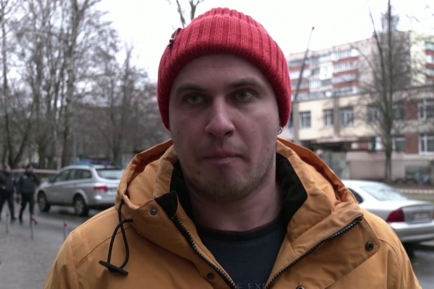 A man in yellow coat and red beanie.