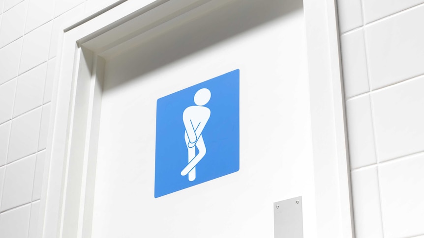 A white toilet door, surrounded by white tiles, is adorned with a blue sign featuring a white figure standing crossed legged.