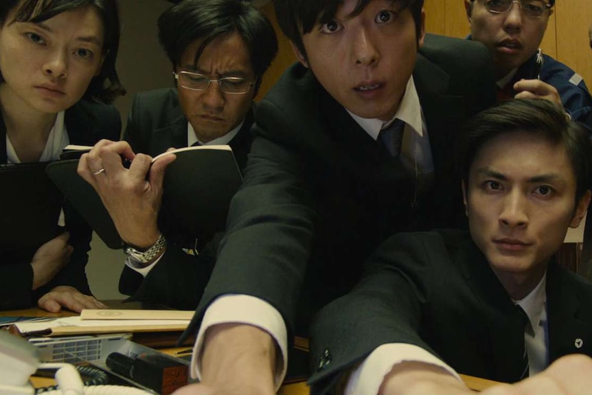 Shocked Japanese workers in an office in a scene from the 2016 film Shin Godzilla.