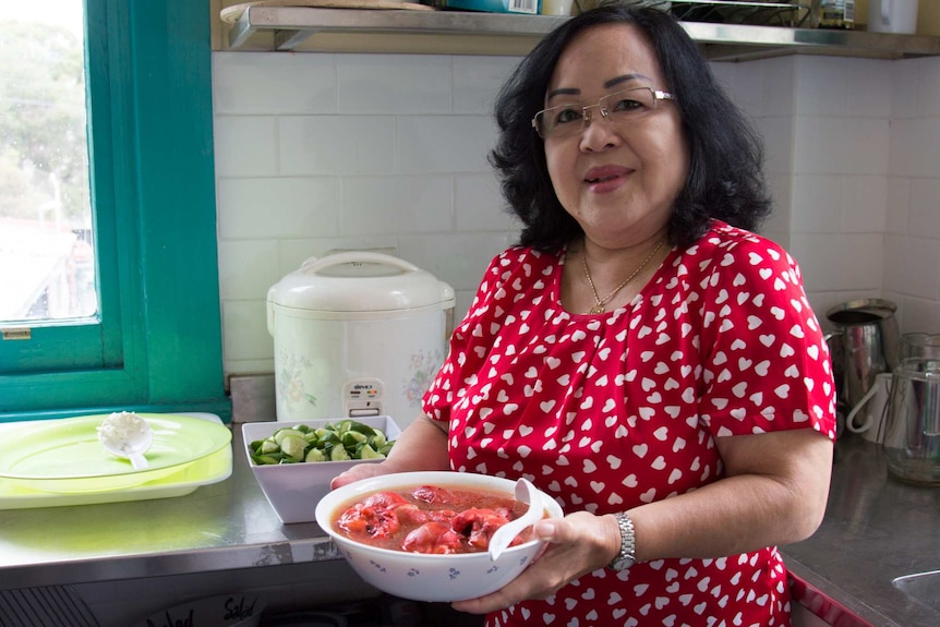 Eveline Giok holds a bowl of ayam cao in a kitchen