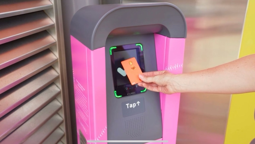 An image of a person holding up a go card to pink and black ticket reader