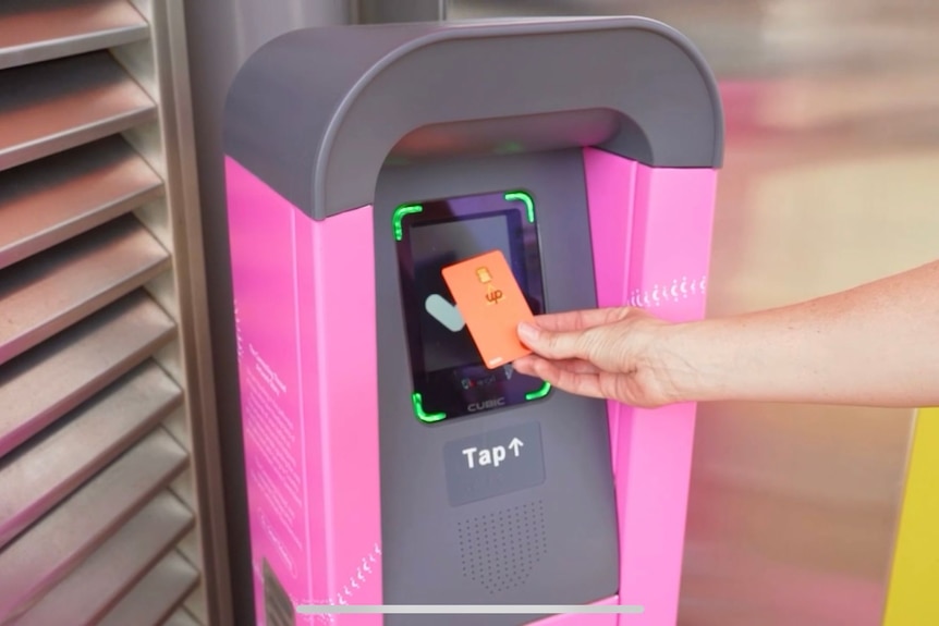 An image of a person holding up a go card to pink and black ticket reader