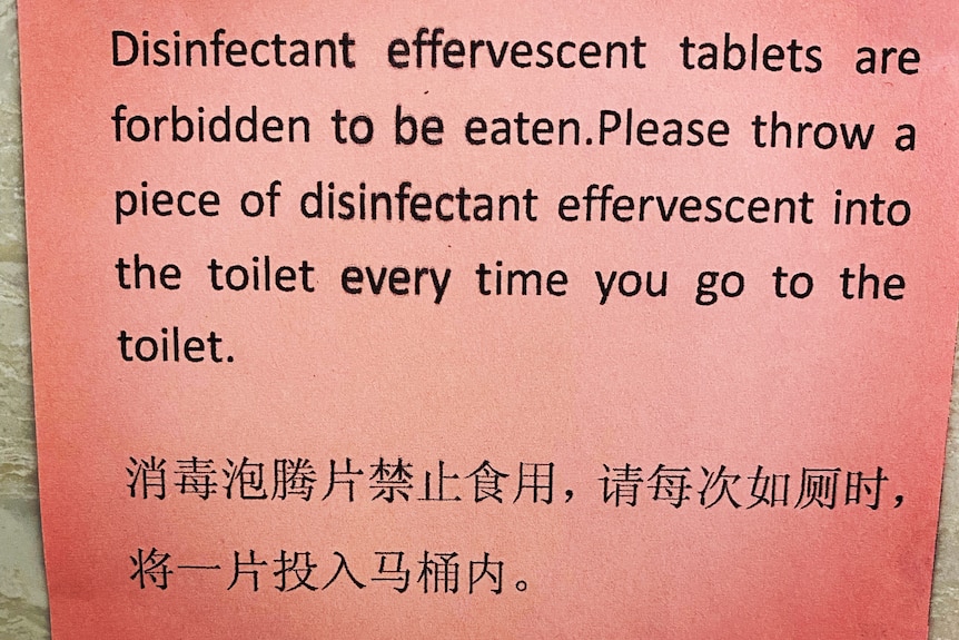 A sign tells toilet users not to eat disinfectant tablets and reminds them to throw one into the toilet at each use.