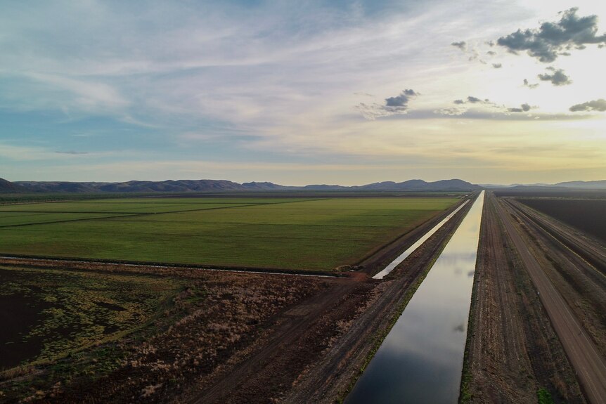 a drone shot of an irrigation channel with paddocks next to it.