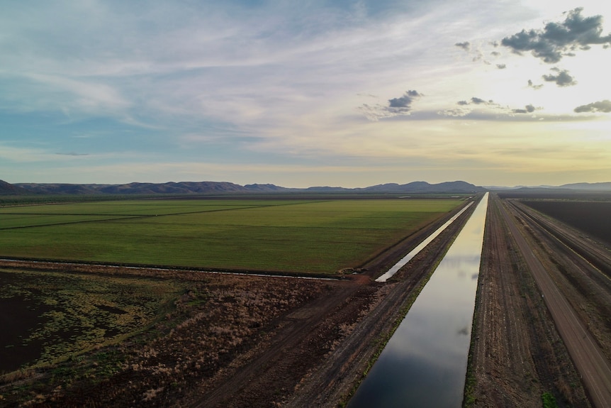 A drone shot of an irrigation channel with paddocks next to it.