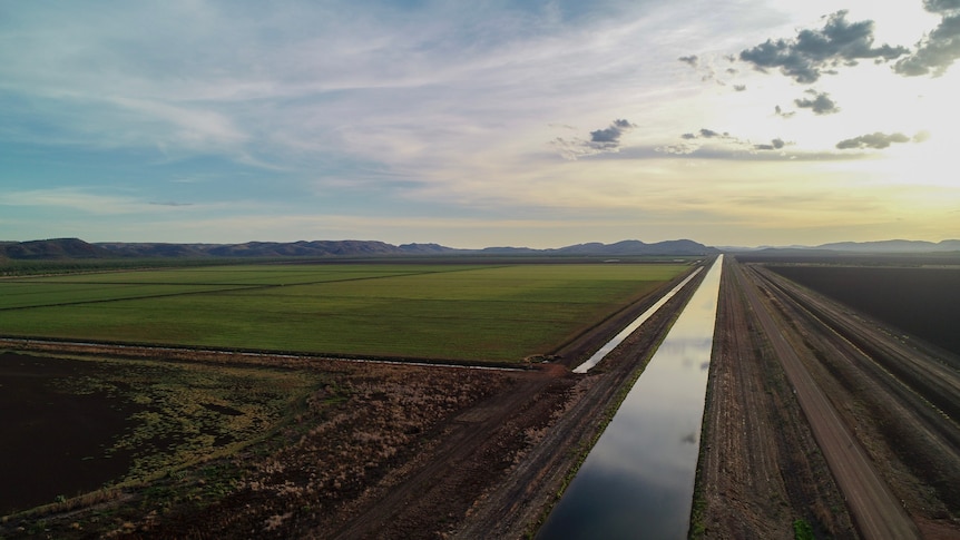 A drone shot of an irrigation channel with paddocks next to it.