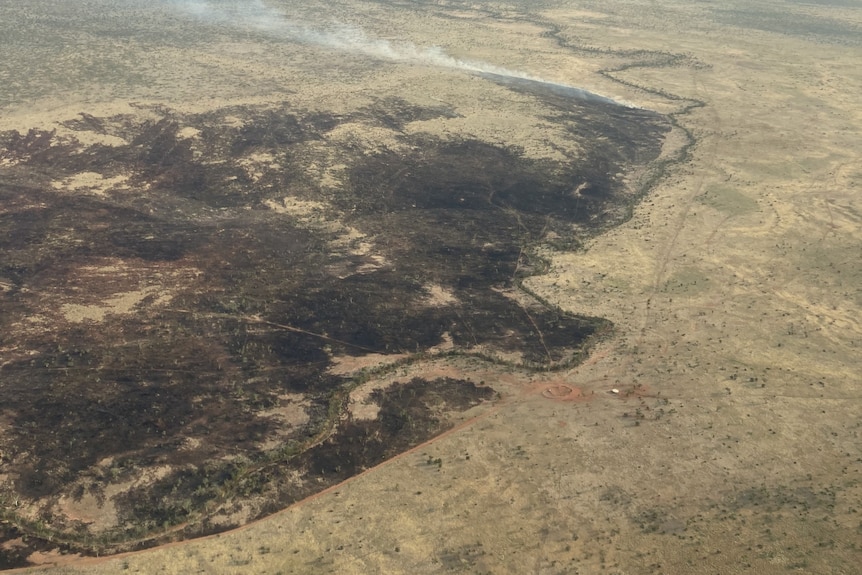 An aerial shot of a massive scar left in grazing land by a fire.