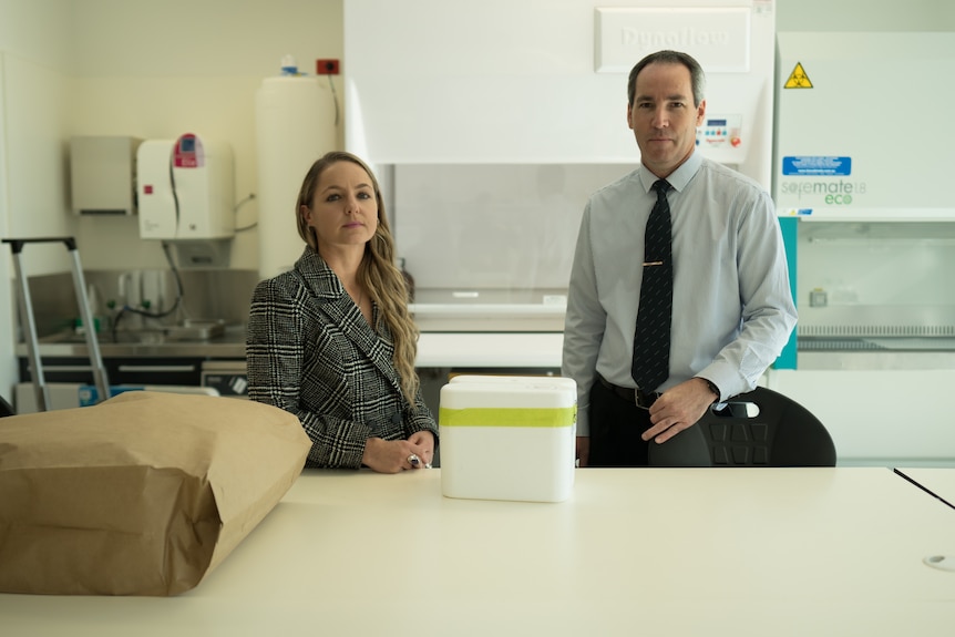 Woman and man standing behind a white bench.