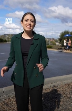 A reporter explains about the arrival of passengers in Perth on a video