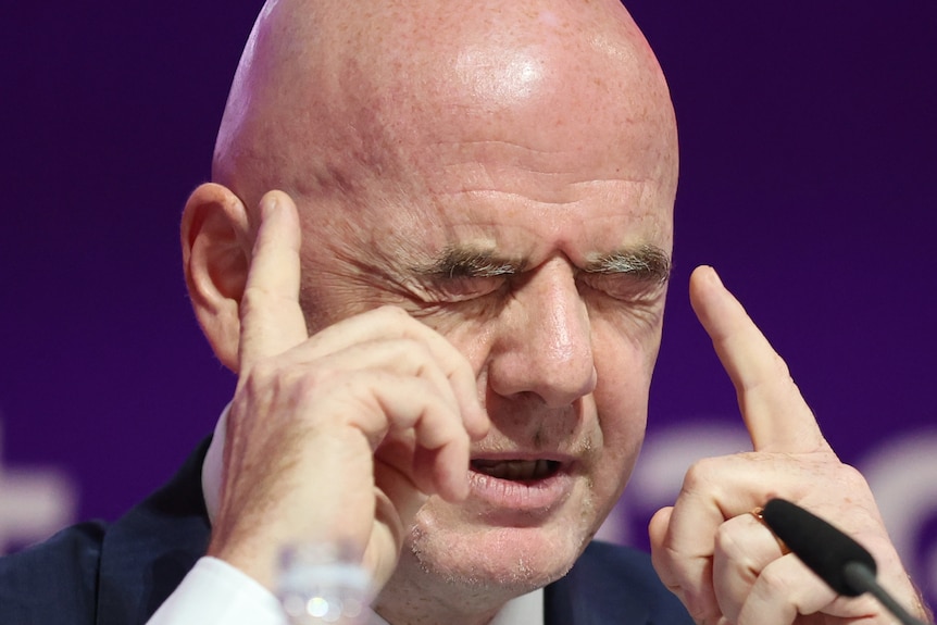 Gianni Infantino closes his eyes and points his fingers to his temples.