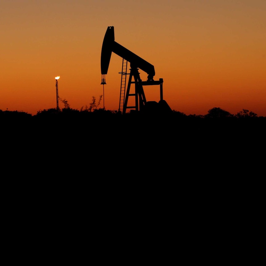 An oil pump sits idle against an orange sky.