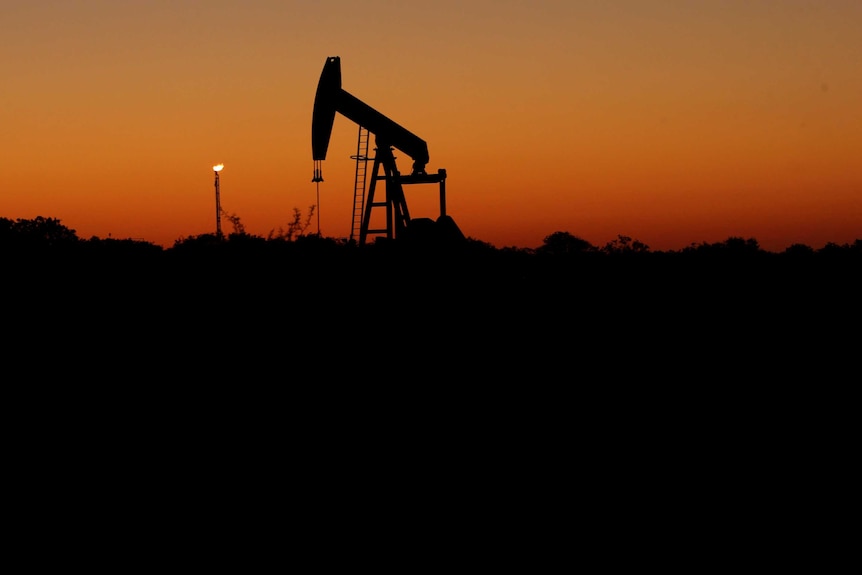 An oil pump sits idle against an orange sky.