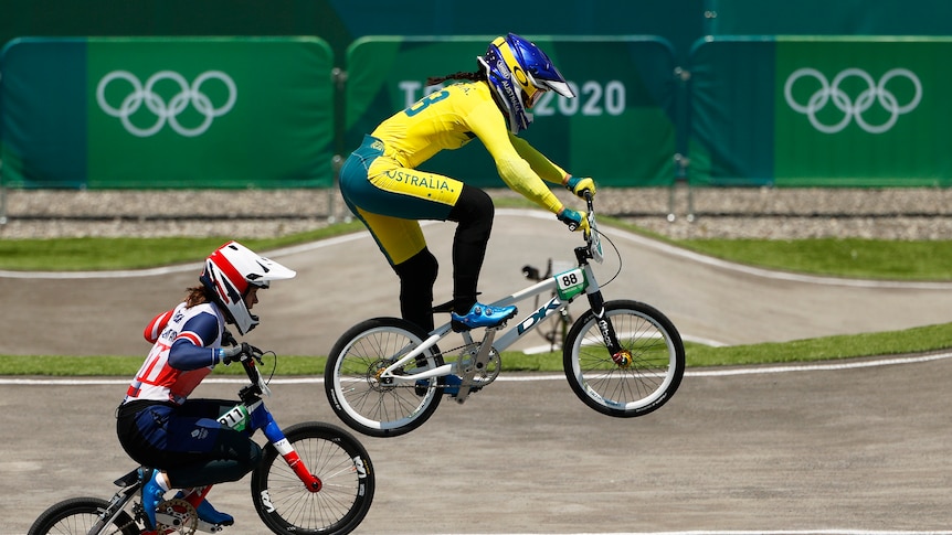 A woman wearing yellow rides a bike in the air