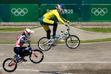 A woman wearing yellow rides a bike in the air