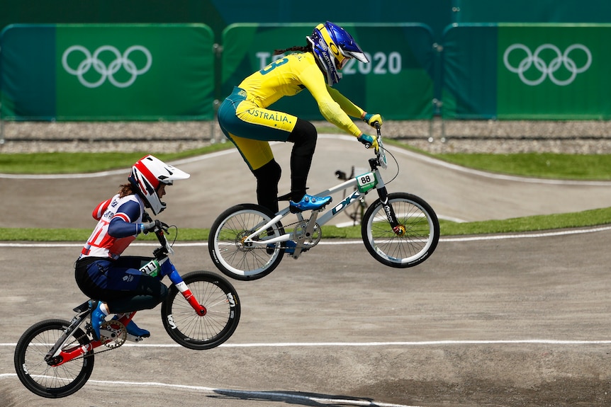 A woman wearing yellow rides a bike in the air