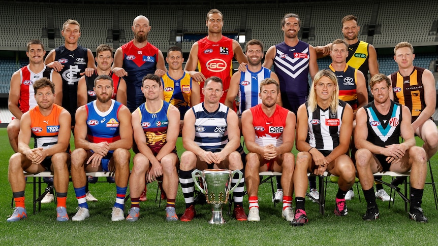 Captains of all 18 AFL clubs pose for a photo on a football field