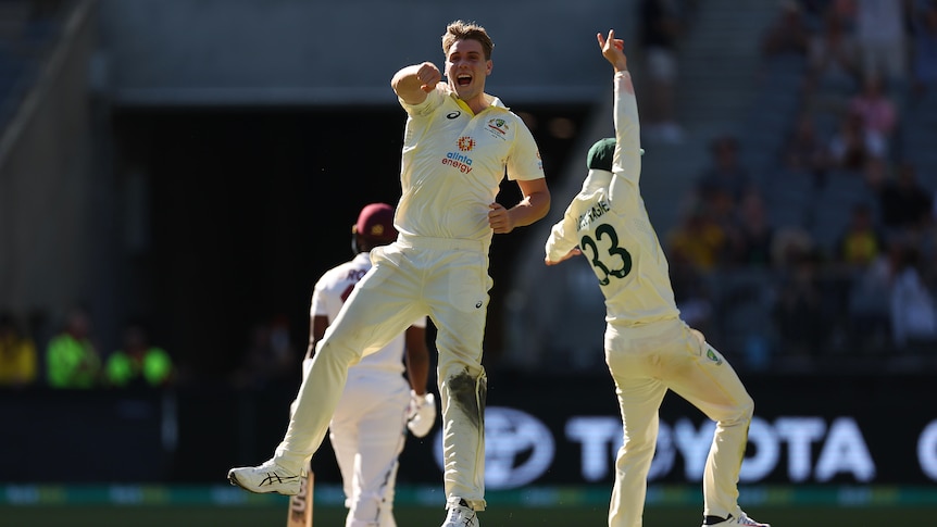 Australia bowler Cameron Green jumps in the air as he celebrates a wicket with teammates during a Test against West Indies.