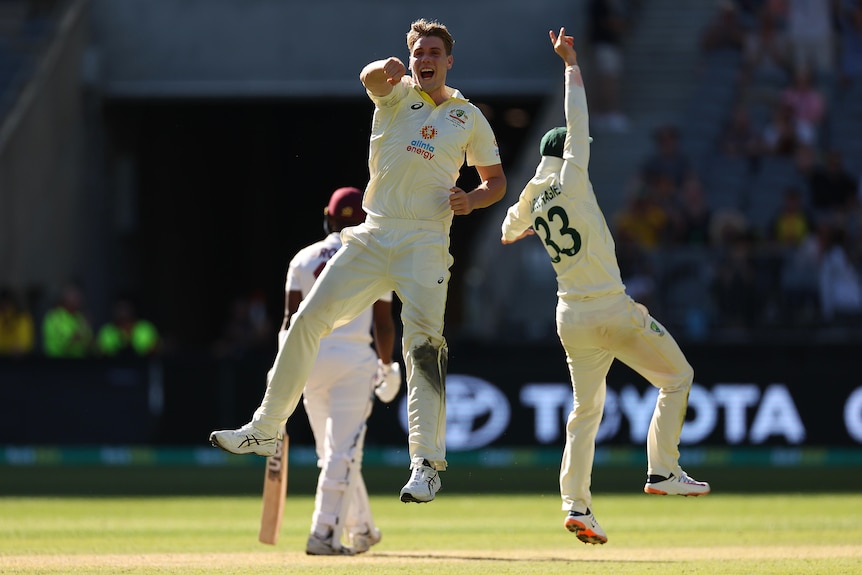 Australia bowler Cameron Green jumps in the air as he celebrates a wicket with teammates during a Test against West Indies.