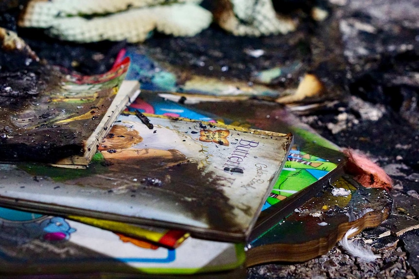 Burnt children's books lie on a flloor.