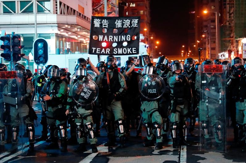 Police man shielded and with tear smoke in a protest in Hong Kong.