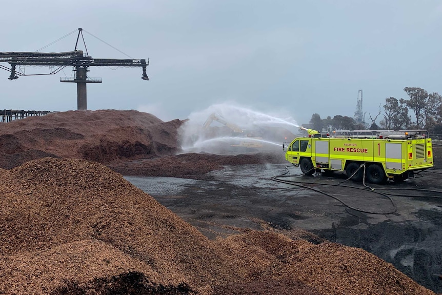 a fire truck sprays water over a pile of woodchips