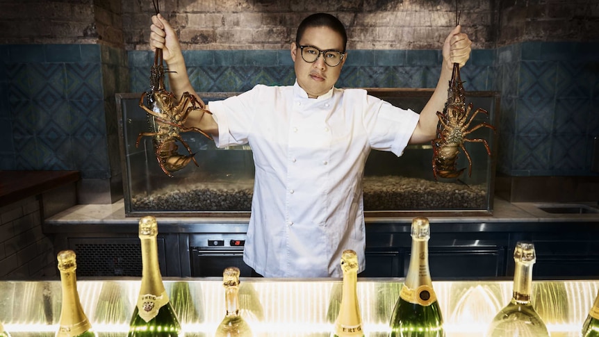 A chef holding two lobsters