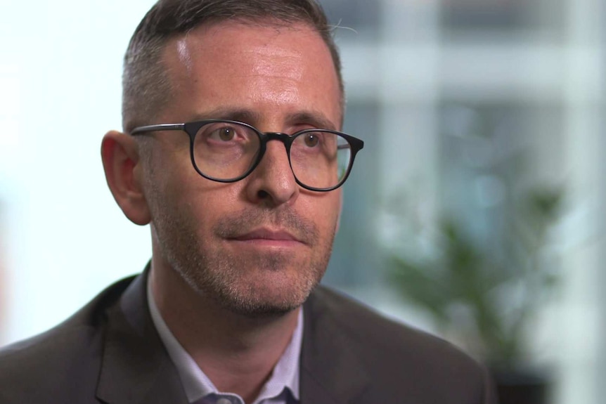 Head shot of wearing glasses and suit with no tie