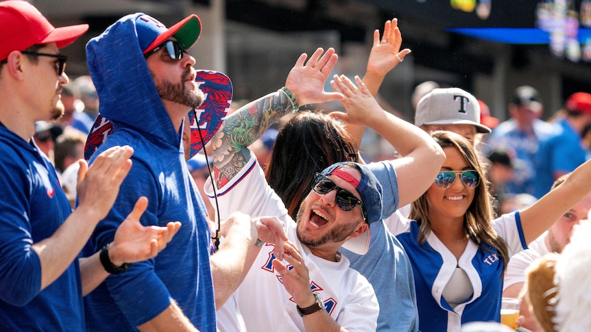 Men and women wearing blue and white smile and raise their hands without wearing masks