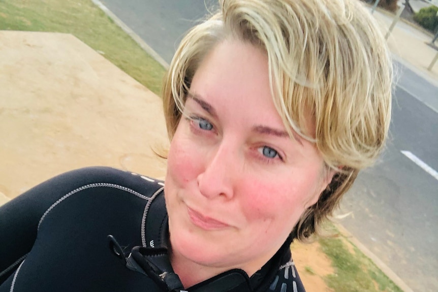 A middle-aged woman with blonde hair wearing a black wetsuit