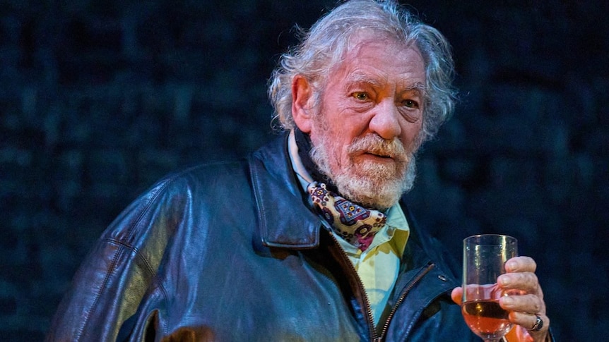 Ian McKellen in a leather jacket holding a glass. 