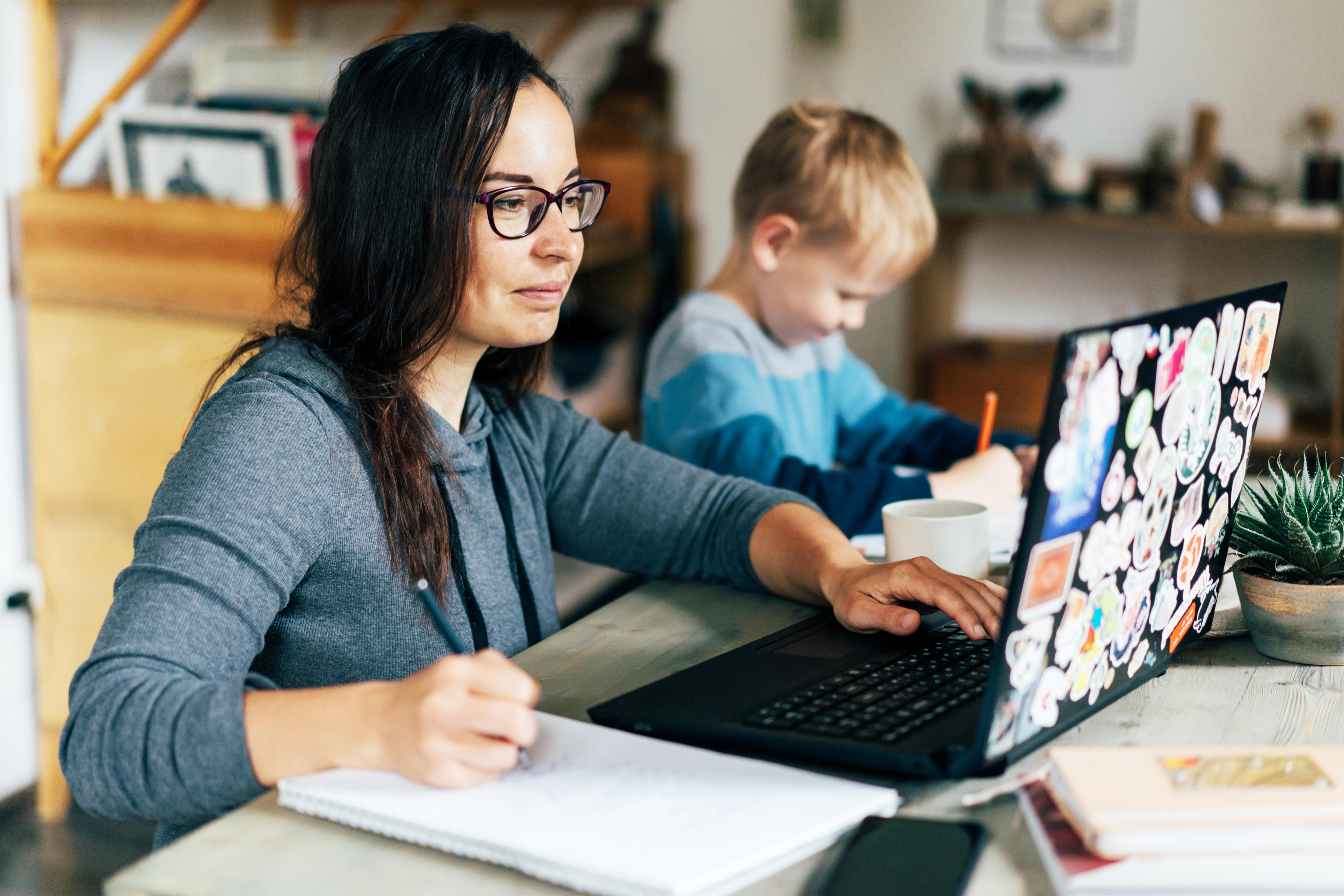 Woman working at home with a kid and a laptop in a story about stepping back and the benefits.