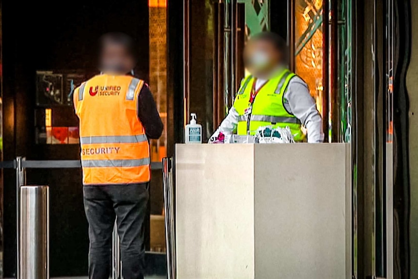 Security guards outside a  hotel hosting returned travellers in quarantine.