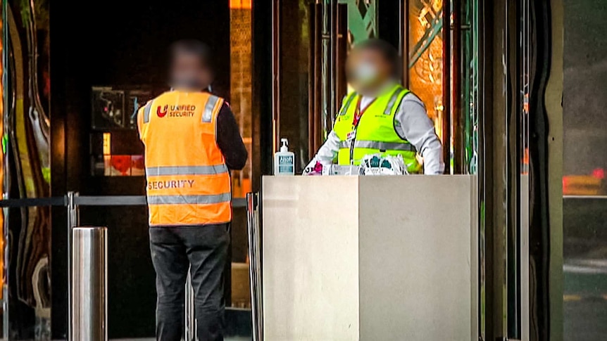 Security guards outside a  hotel hosting returned travellers in quarantine.