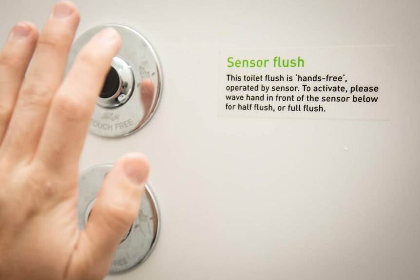 A sensor flush button on a public toilet.