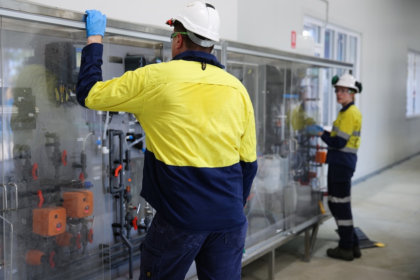 Staff in hard hats and hi-vis jackets showing off infrastructure in a laboratory environment