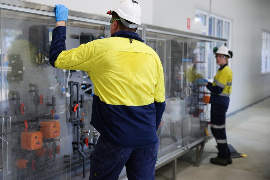 Staff in hard hats and hi-vis jackets showing off infrastructure in a laboratory environment