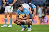 NRL player David Fifita, on his haunches, with his mouth guard hanging from his mouth, has he look tired and disappointed
