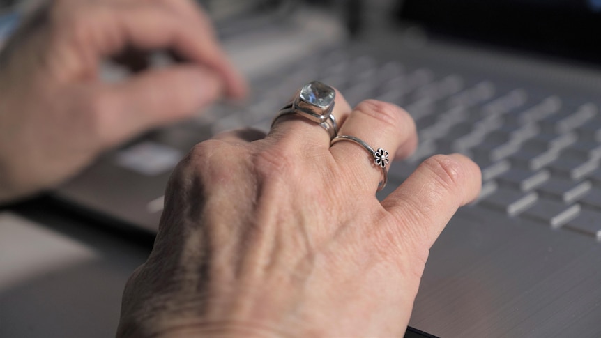 female hands with rings on fingers on laptop keyboard