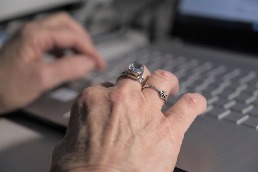 female hands with rings on fingers on laptop keyboard