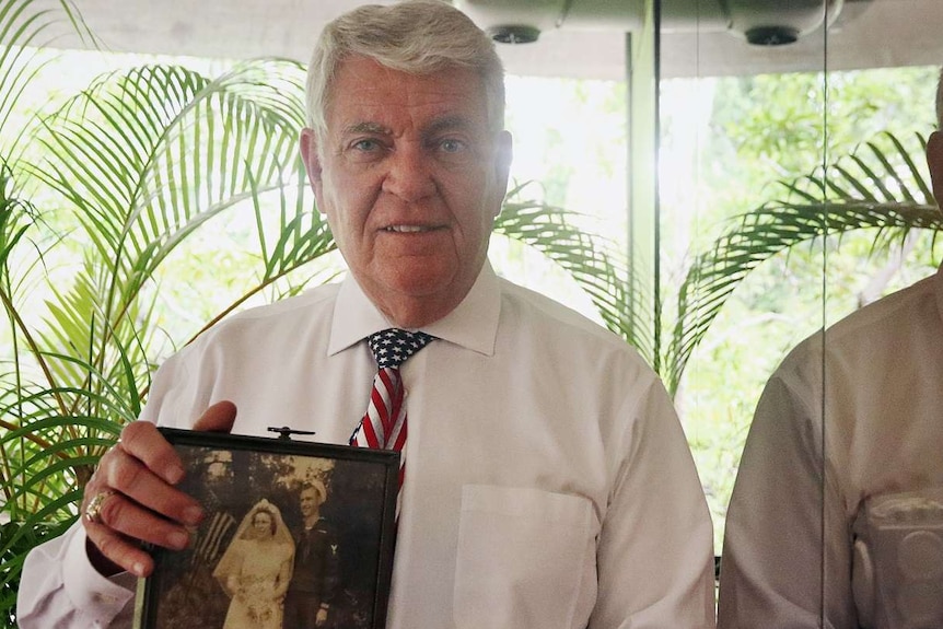 Sam Logan holds up a photo of his mother and father.