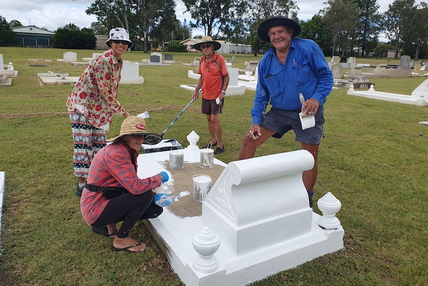 People with paintbrushes painting graves