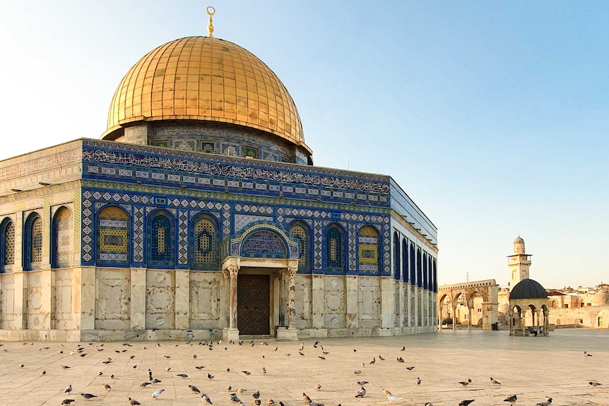 A building with golden dome and colourful exterior decorated with Arabic calligraphy