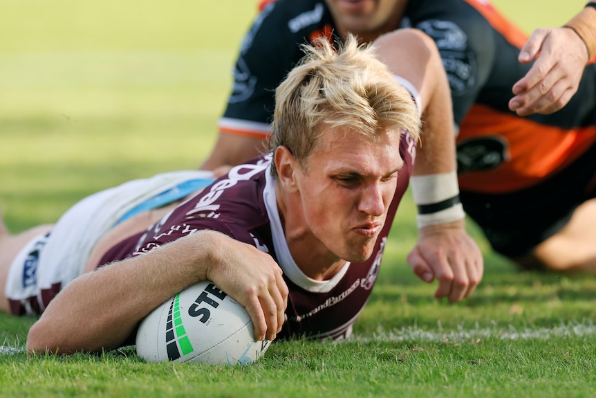 A Manly Sea Eagles NRL player grounds the ball to score a try against Wests Tigers.